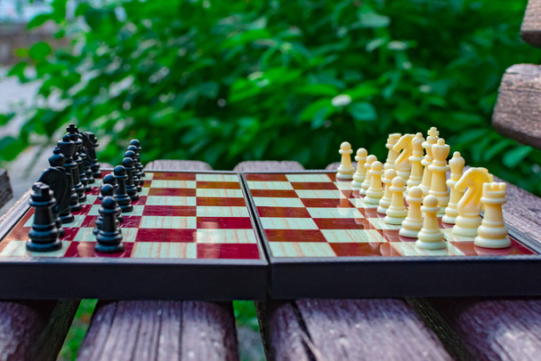 Día de Shehamat. Las piezas de ajedrez se colocan en un tablero de ajedrez sobre un fondo borroso de la naturaleza. Enfoque borroso. Desenfocar. - Foto, imagen