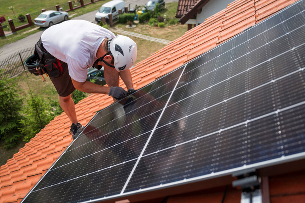 Ingénieur sur le toit de la maison assemble le panneau photovoltaïque. - Photo, image