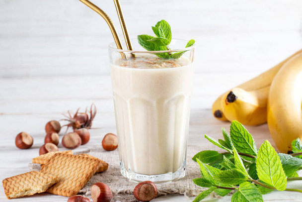 Photo of fresh Made Banana Smoothie on a wooden table with cookies and banana. Milkshake. Protein diet. Healthy food concept, space for text. - Photo, Image