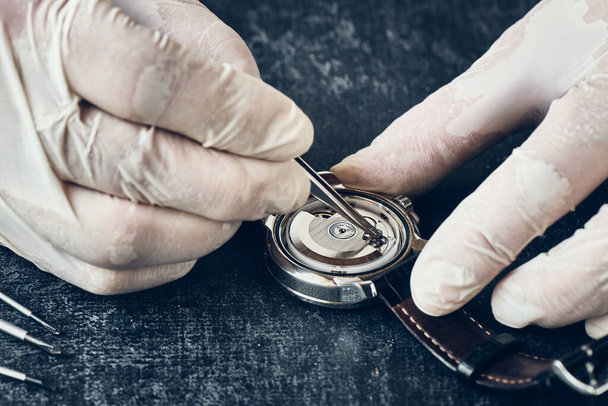 Detalles del trabajo relojero con pinzas en guantes de vinilo, macro, reparación de relojes de pulsera - Foto, imagen