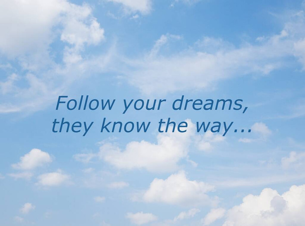 witte wolken en een blauwe lucht met een boodschap 'volg je dromen, ze kennen de weg' - Foto, afbeelding