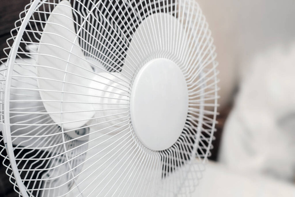 Bílý ventilátor s lopatkami pro chlazení místnosti v teple na dřevěném pozadí. - Fotografie, Obrázek