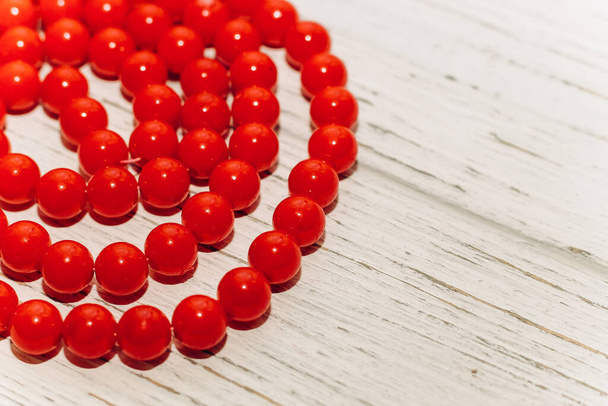 Red large beads in a necklace on a wooden background. - Photo, Image