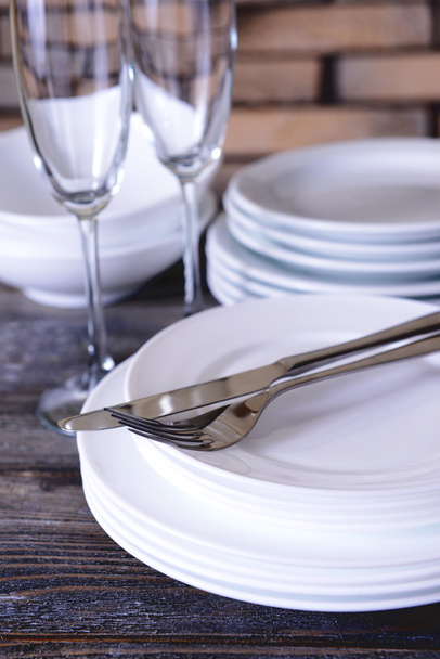 Set of white dishes on table on brick-wall background - Φωτογραφία, εικόνα