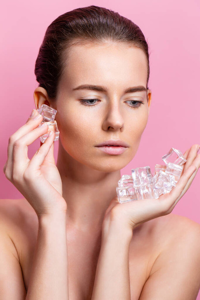Beautiful woman with natural looking makeup holding ice cubes near face - Foto, Imagem