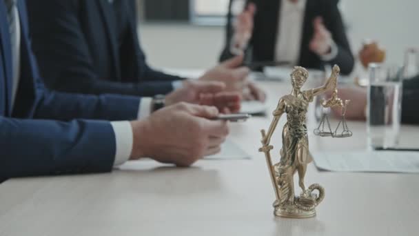 PAN close-up του χρυσού αγάλματος της Θεάς της Femida της Δικαιοσύνης με κλίμακες στο τραπέζι συνεδριάσεων δικηγόρων κατά τη διάρκεια της συνάντησής τους - Πλάνα, βίντεο
