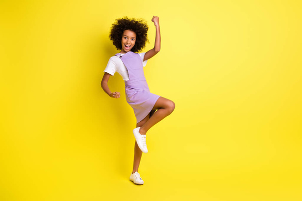 Full length photo of little girl raise fist open mouth wear violet overall isolated yellow color background - Valokuva, kuva