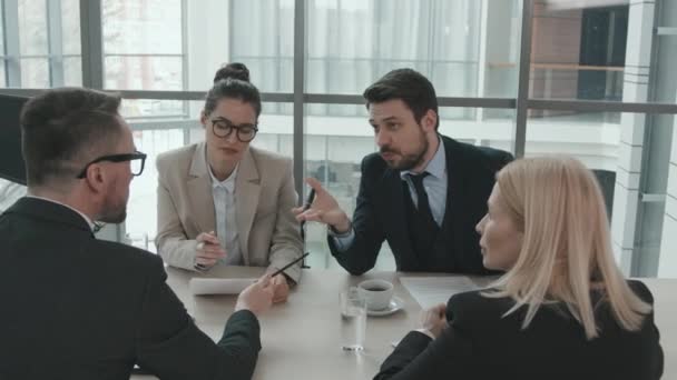 現代のガラス会議室のテーブルに座って法的問題の議論を加熱している若い男性と女性の弁護士の中ショット - 映像、動画