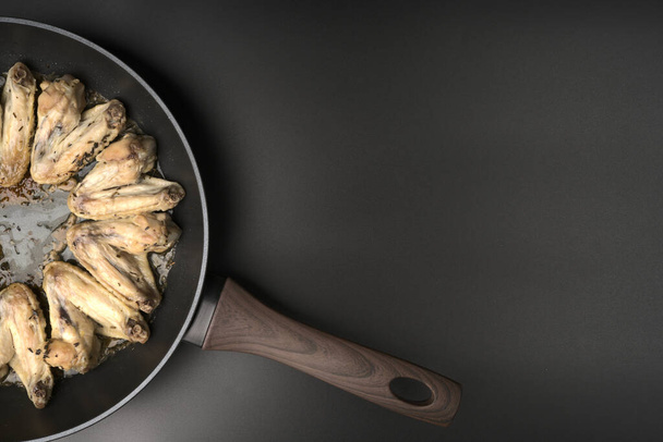 Fried chicken wings lie on a frying pan top view. - 写真・画像