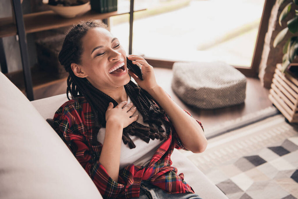 Portrait of attractive cheerful girl sitting on sofa calling friend laughing hilarious story at modern loft industrial flat house home indoors - Фото, зображення