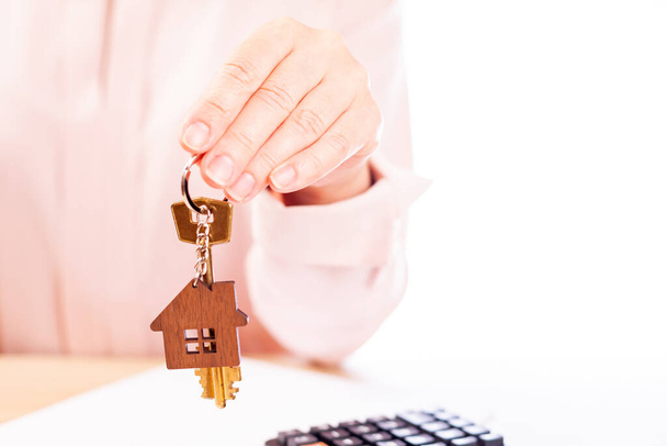 A woman holds the key to the house, the real estate agent, the place under the text - Foto, Imagen