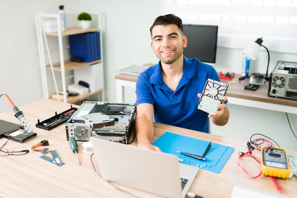 Porträt eines gut aussehenden jungen Mannes, der lächelt, während er ein Datenbackup auf einem Laptop macht und an technischer Unterstützung arbeitet - Foto, Bild