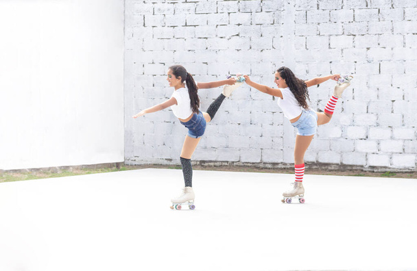 Две забавные девушки-латиноамериканки танцуют на роликах - Фото, изображение