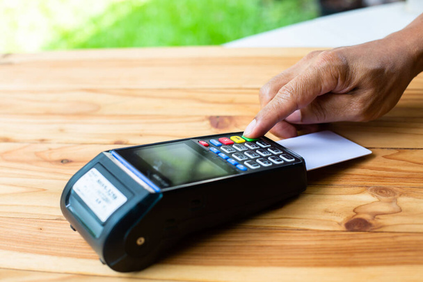 Selektiver Fokus auf Hand legte Kreditkarte In Schlitz des Kreditkartenlesers, Kreditkartenzahlung, Kauf und Verkauf von Produkten und Dienstleistungen, das Konzept der Zahlung ohne Bargeld. - Foto, Bild