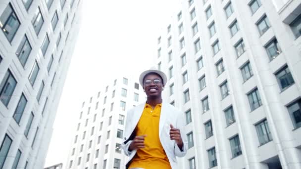 Афроамериканский исполнитель танцует на площади между зданиями - Кадры, видео