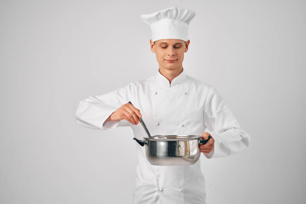 Ένας άντρας με στολή σεφ με ένα τηγάνι στα χέρια του να ετοιμάζει εστιατόριο. - Φωτογραφία, εικόνα