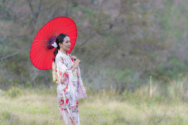 Японская девушка в кимоно с красным зонтиком весной, Япония. Азиатские туристки. - Фото, изображение