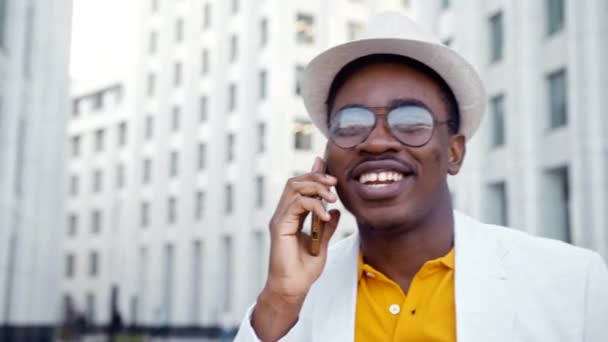 Gioioso uomo afroamericano in giacca e cravatta parla su smartphone - Filmati, video