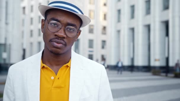 Poważny czarny mężczyzna w klasycznym garniturze i okularach wygląda prosto - Materiał filmowy, wideo