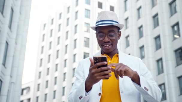 アフリカ系アメリカ人の男がスマートフォンを見て笑顔で - 映像、動画