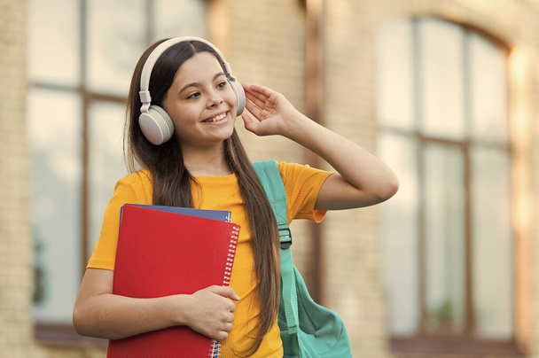 Modern child girl with headphones back to school hold textbook, audio lesson concept - Φωτογραφία, εικόνα