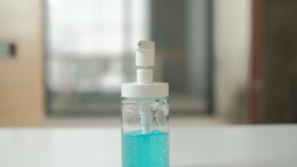 Estrarre mossa VDO, alcool gel blu in una bottiglia di plastica trasparente su una scrivania bianca in ufficio. Pulire le mani per prevenire la diffusione e l'infezione di batteri, coronavirus (Covid-19), e sano. - Filmati, video