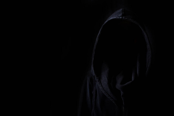 Las caras no son visibles en túnicas negras en la oscuridad sobre un fondo negro. - Foto, Imagen