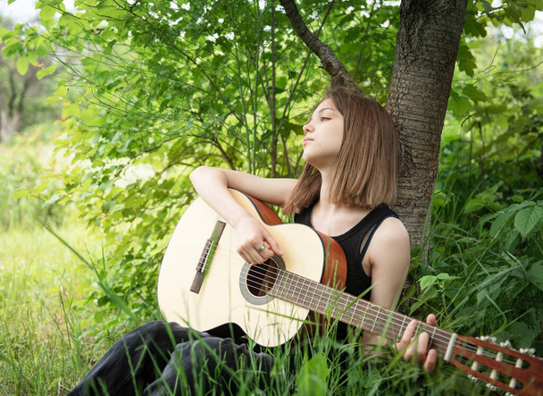 Teenager girl playing guitar in the park - Zdjęcie, obraz