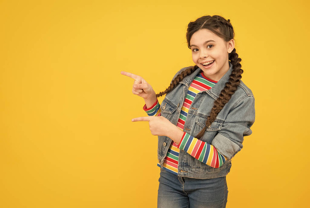 Excited little girl with braids wear denim clothes, promoting goods concept - Zdjęcie, obraz