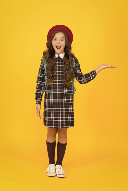 surprised little girl in school uniform, presenting product - Foto, Bild