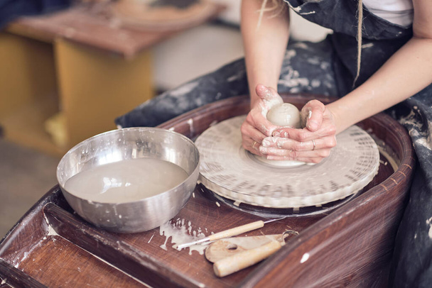 In Großaufnahme stellen weibliche Hände Geschirr aus Ton her. Frauenhände arbeiten an der Töpferscheibe. Der Töpfermeister arbeitet in einer Werkstatt - Foto, Bild