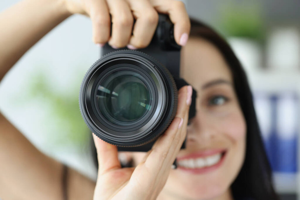 Joven sonriente mujer tomando fotos en negro profesional cámara de primer plano - Foto, imagen