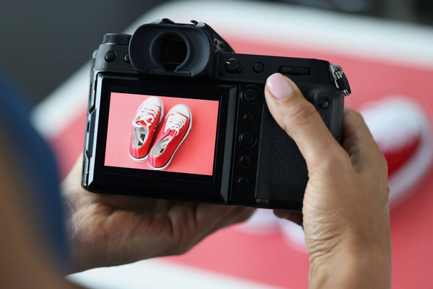 Woman photographing red sports shoes on professional camera closeup - Photo, Image