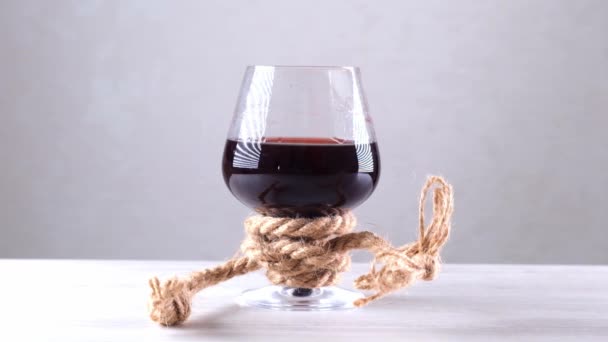 Het wijnglas is vastgebonden met een touw. Het begrip alcoholverslaving. - Video