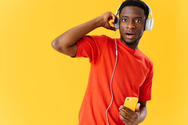 homem de aparência africana em fones de ouvido ouvindo música isolado fundo - Foto, Imagem