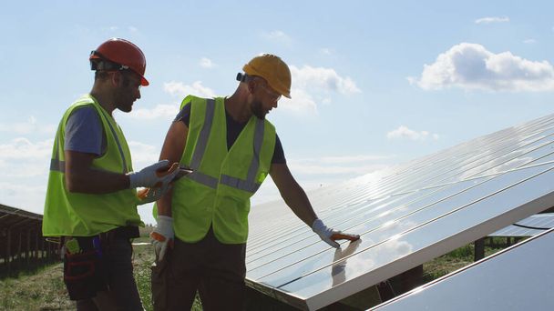 Male engineers inspecting photovoltaic panel together - Photo, Image