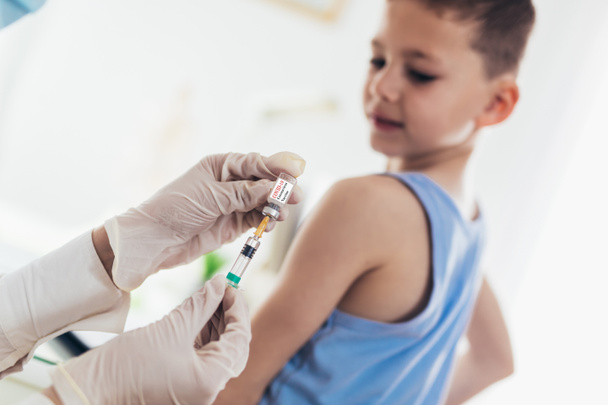 Вакцинація від коронавірусу. Вакцина від Covid-19. Лікар щеплює дитину. Маленький хлопчик отримує постріл грипу
. - Фото, зображення