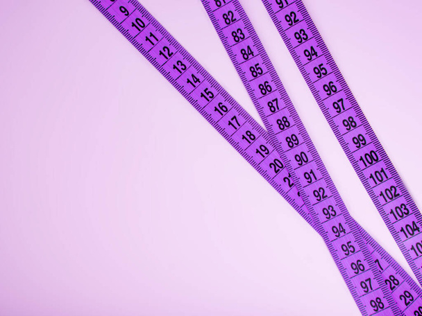 Heldere paarse tape maatregel op violette achtergrond met copyspace - Foto, afbeelding