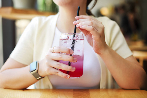Unrecognizable female sitting at restaurant table and drinking fresh cold beverage on weekend day in summer - 写真・画像
