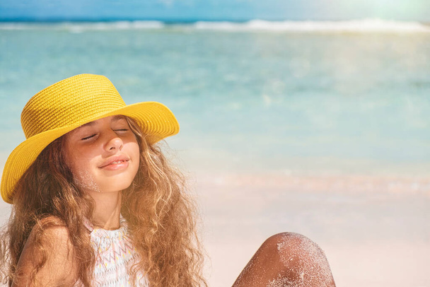 Bikinili ve sarı şapkalı genç kız. Okyanusun kenarında sarı şapkalı, uzun saçlı güzel bir kız. Yaz tatili ve seyahat konsepti - Fotoğraf, Görsel