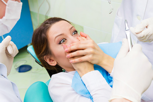 Paciente femenina en consultorio de dentista asustada, temerosa de médico, procedimiento
 - Foto, imagen