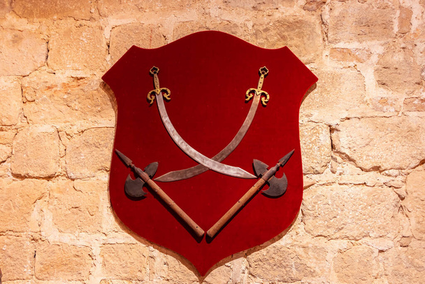 赤いベルベットの盾の上の壁に掛けられた剣と斧 - 写真・画像