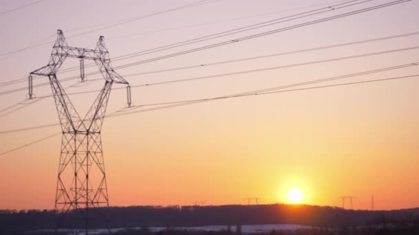 Static footage of setting sun behind horizon. View of high voltage power lines carried by lattice tower. - Footage, Video