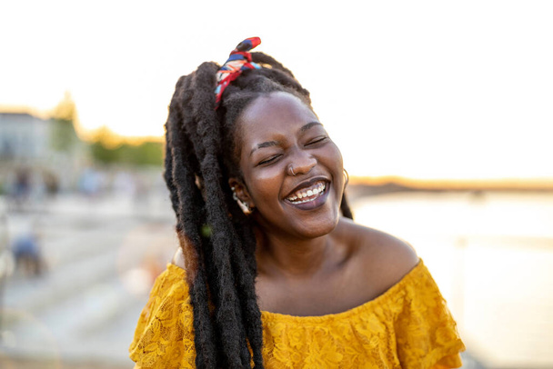 Happy young woman with dreadlocks outdoors - Photo, Image