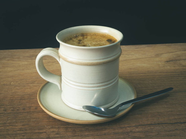 Een kop koffie, in een wit kopje op houten achtergrond, foto wazig achtergrond - Foto, afbeelding