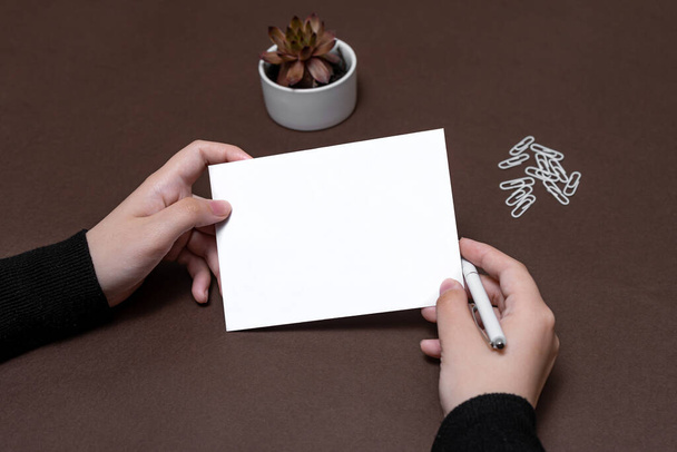 女性の手は空白のノートを保持する新しいメッセージの更新のアイデアを書く。レディーパームエンベロープの表示折り返し文字ポストアドレス. - 写真・画像