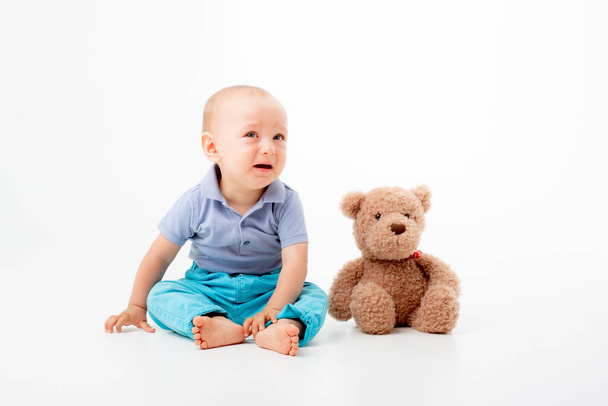 ein kleiner Junge mit einem Teddybär ist auf weißem Hintergrund isoliert - Foto, Bild