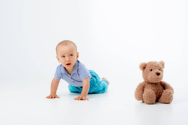 een baby jongen met een teddybeer is geïsoleerd op een witte achtergrond - Foto, afbeelding
