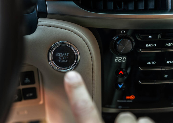 Палець натискає кнопку "Пуск", зупиняє двигун у розкішному автомобілі. Палець чоловіка стискається. Концепція власника та дилера
. - Фото, зображення