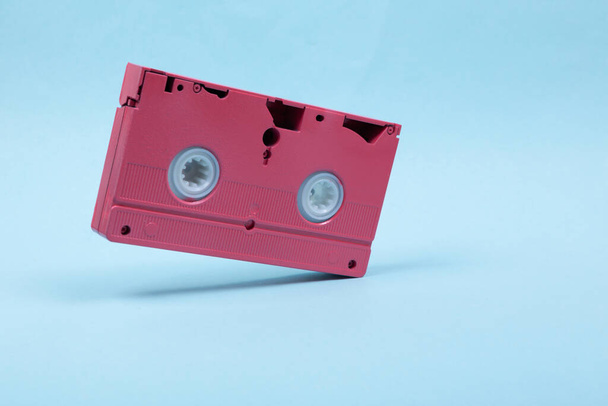 Levitating pink video cassette on blue background. 3D photo. Minimalistic still life. Creative layout. Concept art - Photo, Image